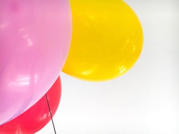 Close-up of colorful helium balloons against white background