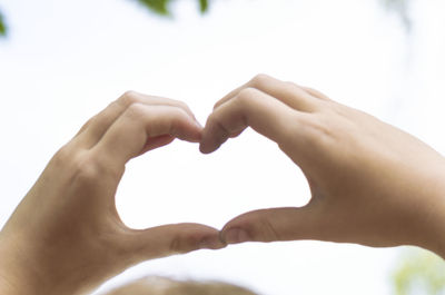 Midsection of woman making heart shape hands