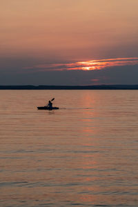 Silhouette boat in sea against orange sky