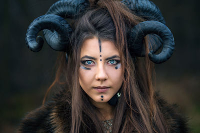 Close-up portrait of serious woman with painted face wearing horns