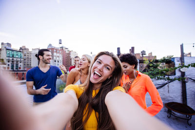 Portrait of smiling young woman against sky