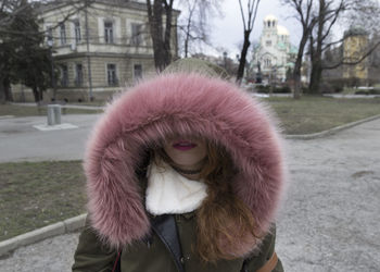 Close-up of young woman with pink fur hood