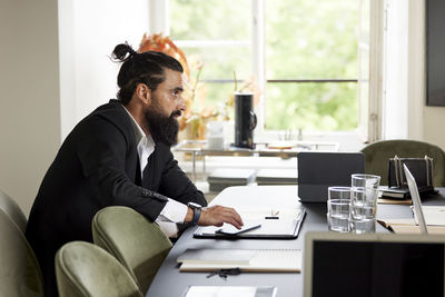 Side view of young man using laptop at home