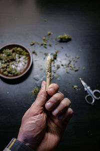 Cropped hands of man holding marijuana joint