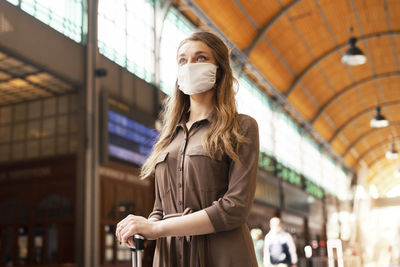 Low angle view of woman wearing mask standing at railroad station