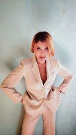 Portrait of a smiling young woman standing against wall