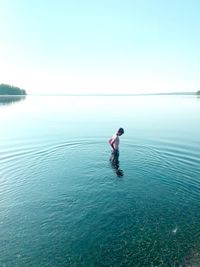 Boy standing in sea against clear sky