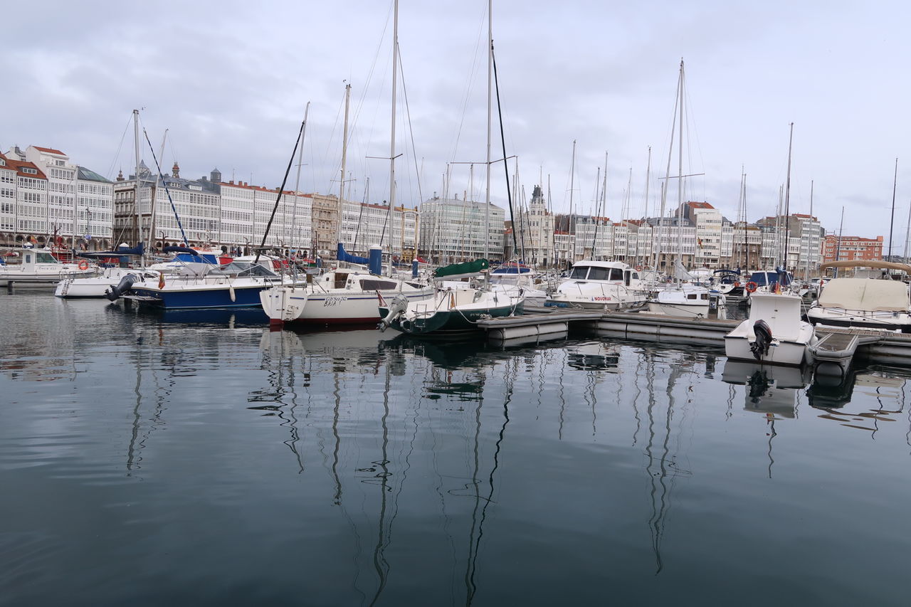 nautical vessel, transportation, mode of transport, moored, reflection, water, mast, boat, harbor, sky, sailboat, waterfront, outdoors, yacht, no people, day, cloud - sky, travel destinations, nature, architecture, sea, building exterior, sailing ship