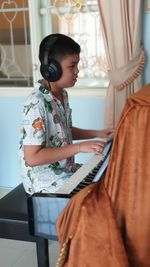 Pratice makes perfect.  side view of a boy playing piano at home.  