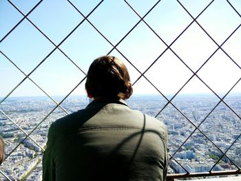 Rear view of man looking at sea against cityscape