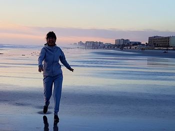 Man standing on beach against sky during sunset