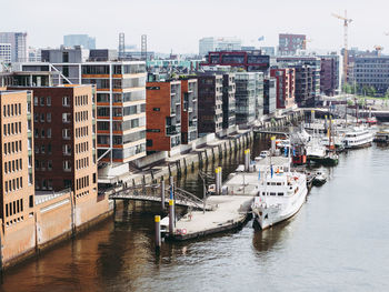 High angle view of boats moored on river by buildings in city against sky