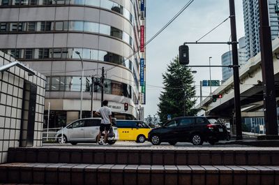 Cars on street in city against sky