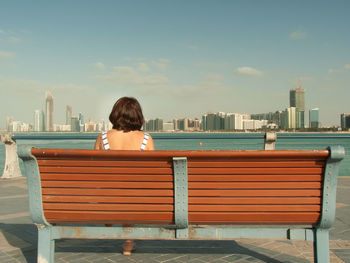 Rear view of woman sitting on bench no pier