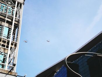 Low angle view of airplane flying in building against sky