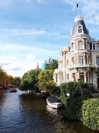 Sailboats moored in river against buildings