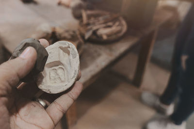 Man molding clay to make ceramics with his hands, artisan working in his workshop, selective focus