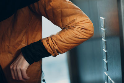 Close-up of man standing against orange wall