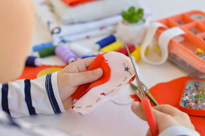 A caucasian boy is learning to sew with his hands a homemade gift for mom for a holiday