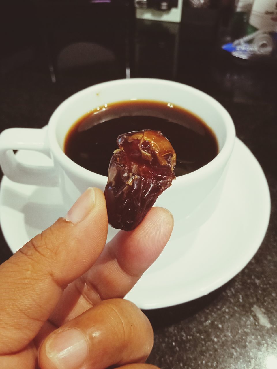 hand, food and drink, one person, holding, food, cup, drink, mug, personal perspective, finger, freshness, refreshment, sweet food, indoors, coffee, coffee cup, sweet, close-up, lifestyles, chocolate, dessert, hot drink, dish, table, kitchen utensil, adult, unhealthy eating, saucer
