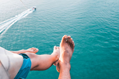 Low section of man and woman paragliding over sea