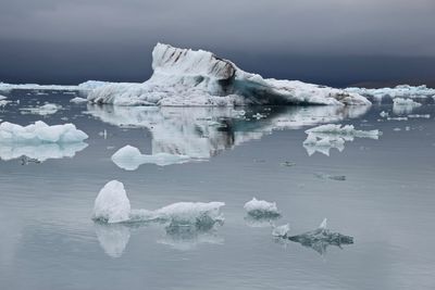 Scenic view of glaciers on lagoon against sky