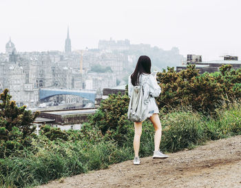 Rear view of woman standing against buildings in city