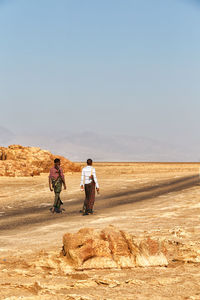 Rear view of men walking on desert