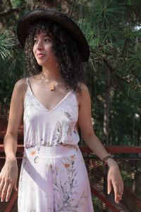 Young woman wearing hat standing against trees