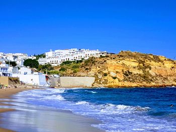 Buildings by sea against clear blue sky