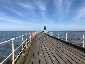 Pier on sea against cloudy sky