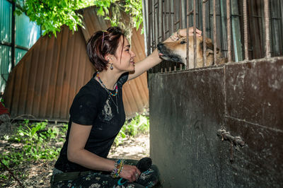 Dog at the shelter.  lonely dogs in cage with cheerful woman volunteer