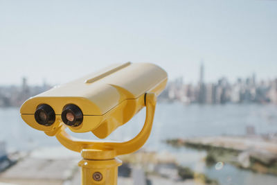 Close-up of coin-operated binoculars against cityscape