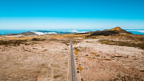 Aerial view of road at desert against blue sky