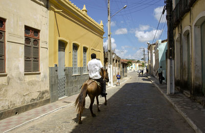 Man riding horse on street in city