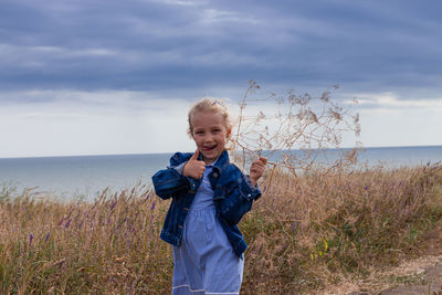 Blond long hair child girl in denim jacket walks on sea landscape. travelling hiking running outdoor