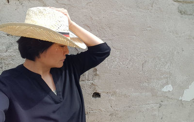 Woman in hat against wall