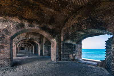 Archway of old building by sea against sky