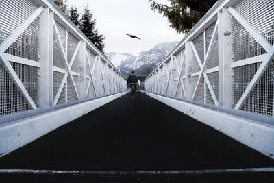 Rear view of man on footbridge against sky