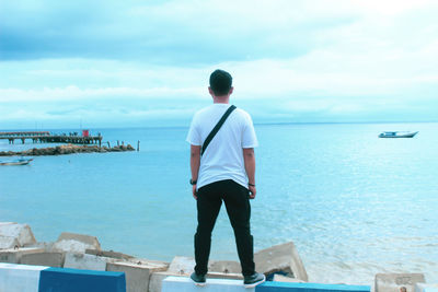 Rear view of man looking at sea against sky