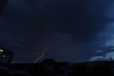 Lightning over buildings at night against dark blue sky