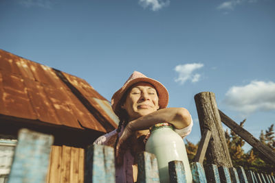 Smiling woman with eyes closed leaning on jar of milk