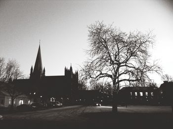 Bare trees and buildings against clear sky