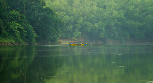 Man on boat in lake against trees