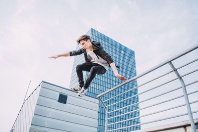 Low angle view of young man jumping against sky