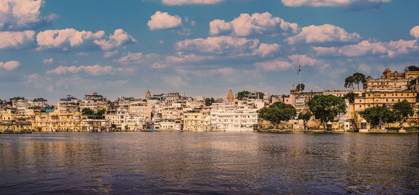 Buildings by river against sky