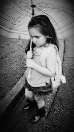 High angle view of smiling girl holding while sitting outdoors