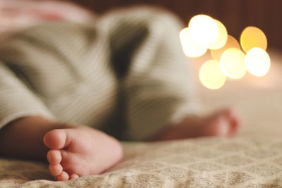 Low section of baby lying on bed