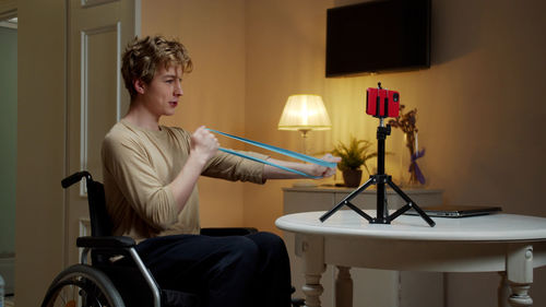 Young man exercising while vlogging at home