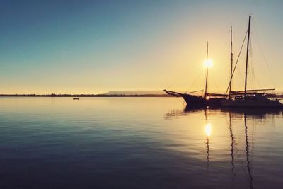 Sailboats in sea against sky during sunset